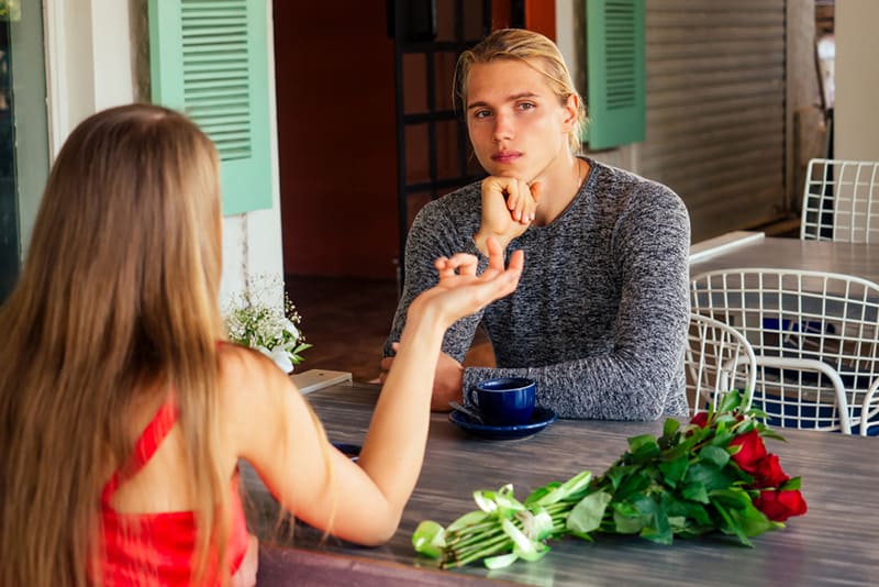 homem perturbado sentado com uma mulher num encontro no café