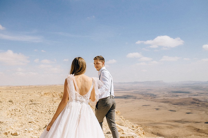 coppia di sposi che si tiene per mano nel deserto