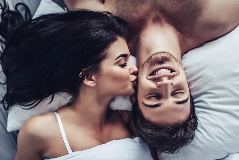 woman kissing her boyfriend in the cheek while he smiling