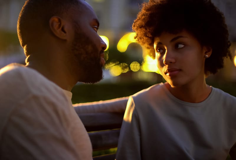 woman looking at the man with hope while sitting together on the bench