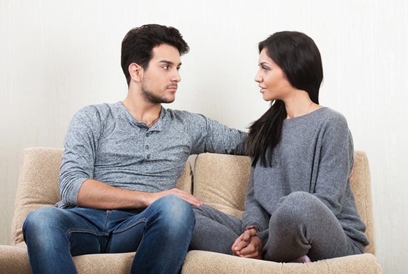 young couple talking while sitting on the sofa together
