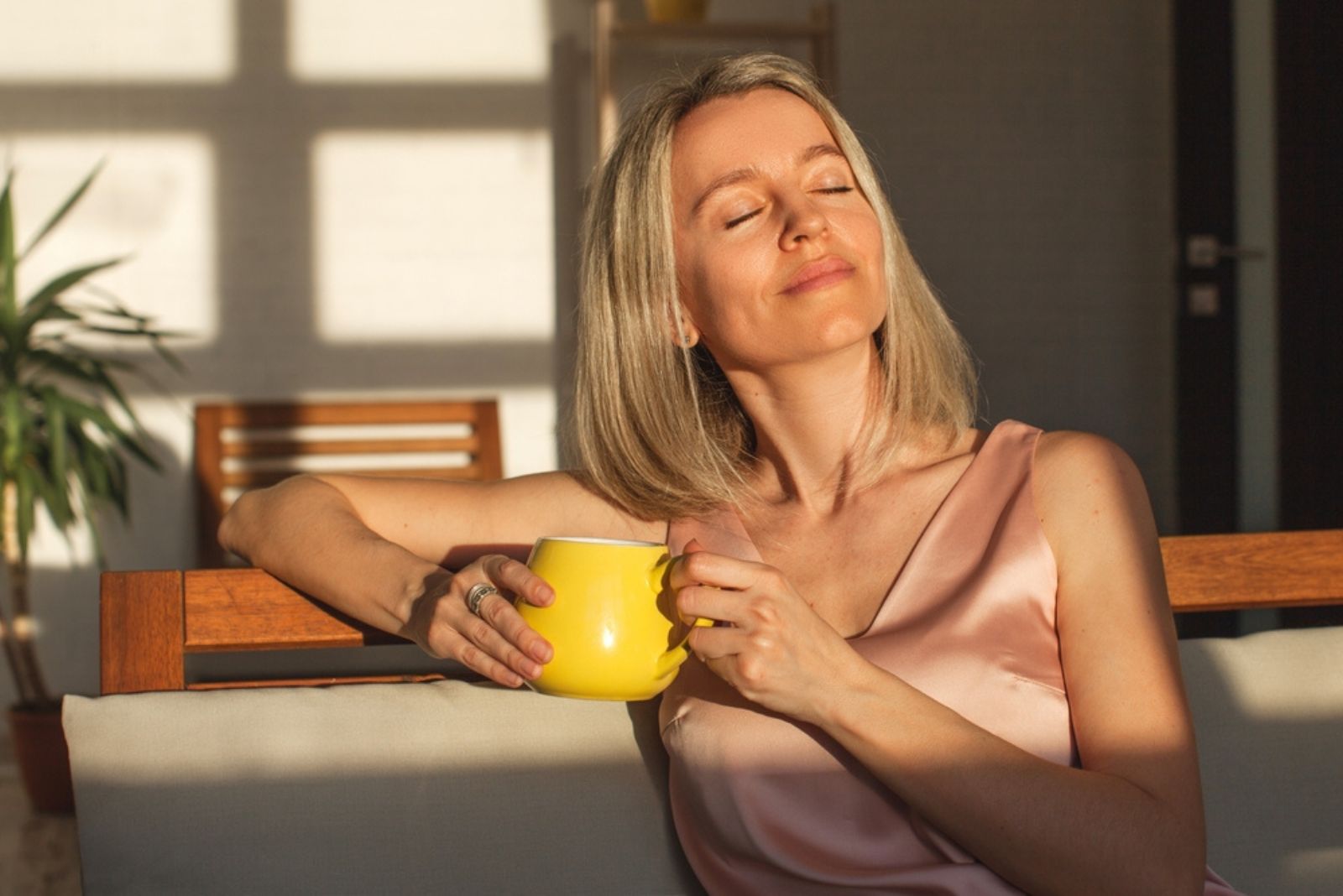 mujer tranquila disfrutando del sol de la mañana y del café