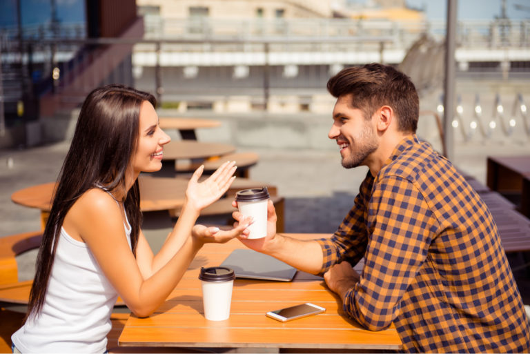 a smiling man and woman sit at a table and talk
