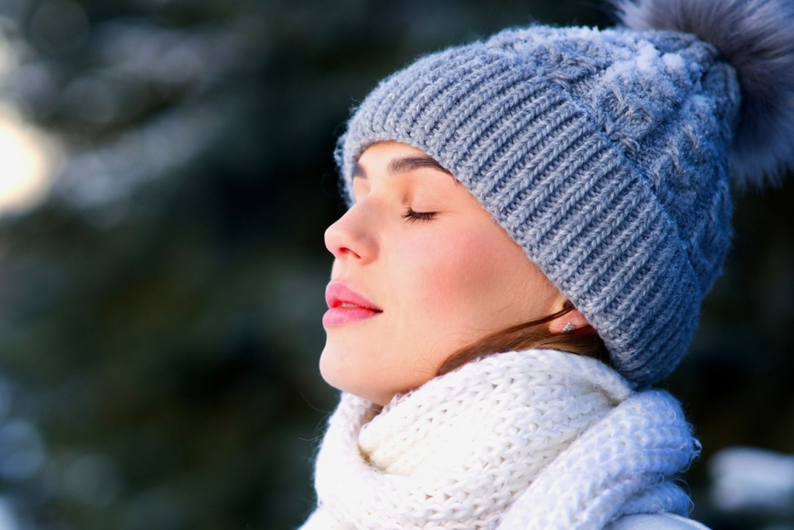 mulher jovem com chapéu mantém os olhos fechados num dia de inverno