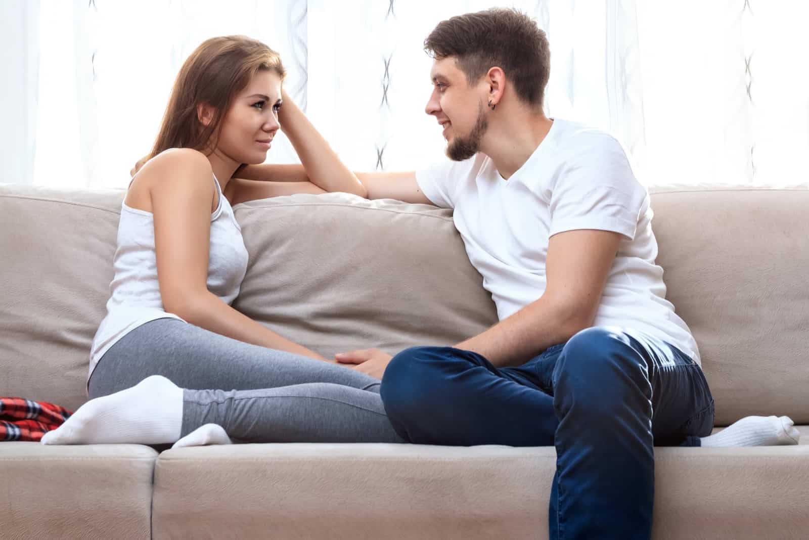 a man and a woman sit on the couch and talk