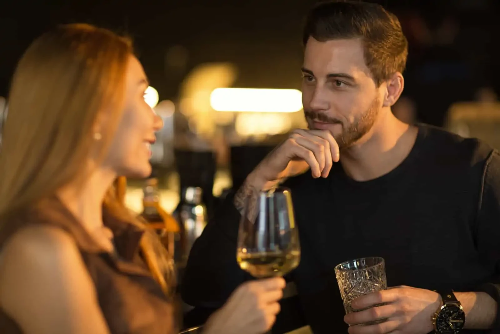 a man talking to a woman while drinking wine