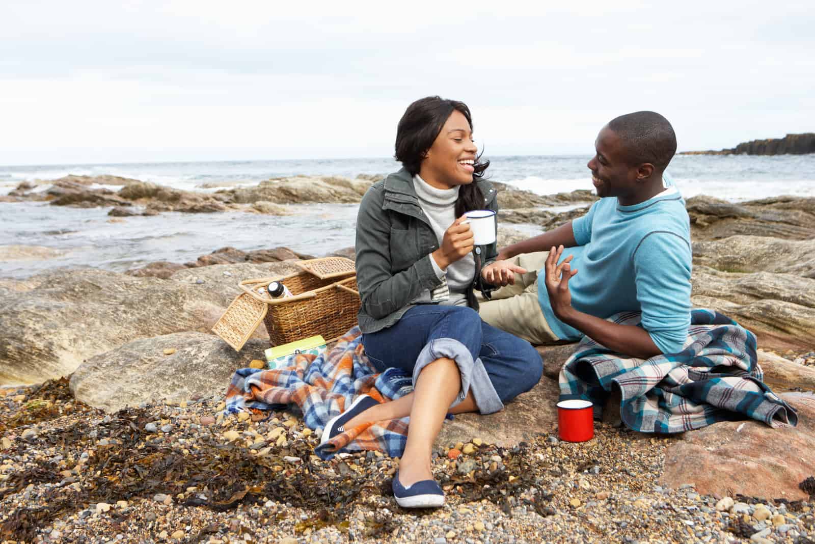 um casal sorridente e amoroso sentado na praia a conversar