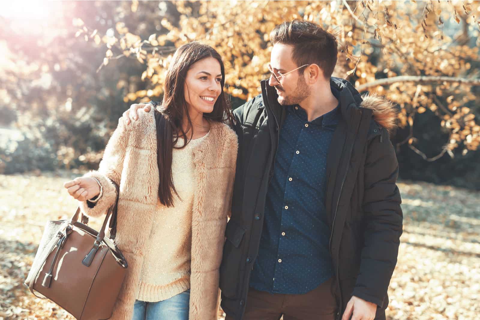 a smiling man and woman walking through the park