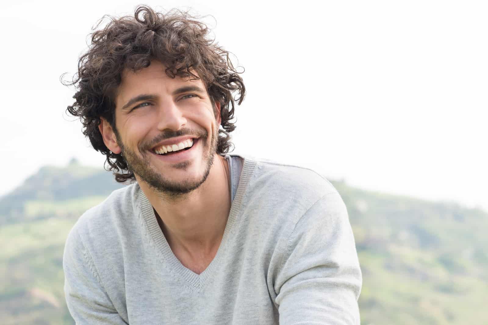 un hombre sonriente se levanta y mira delante de él