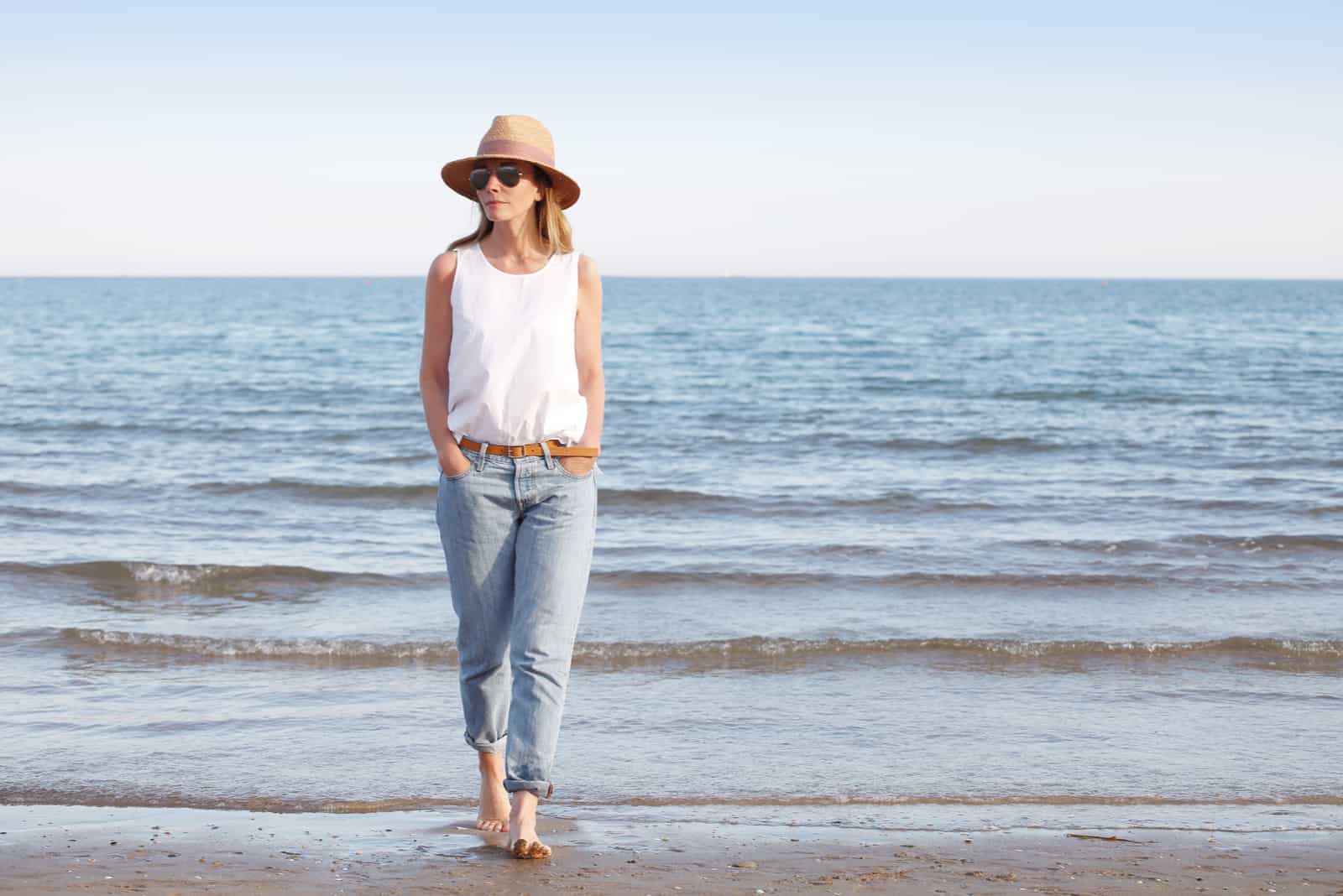 una donna con un cappello in testa apparecchia sulla spiaggia