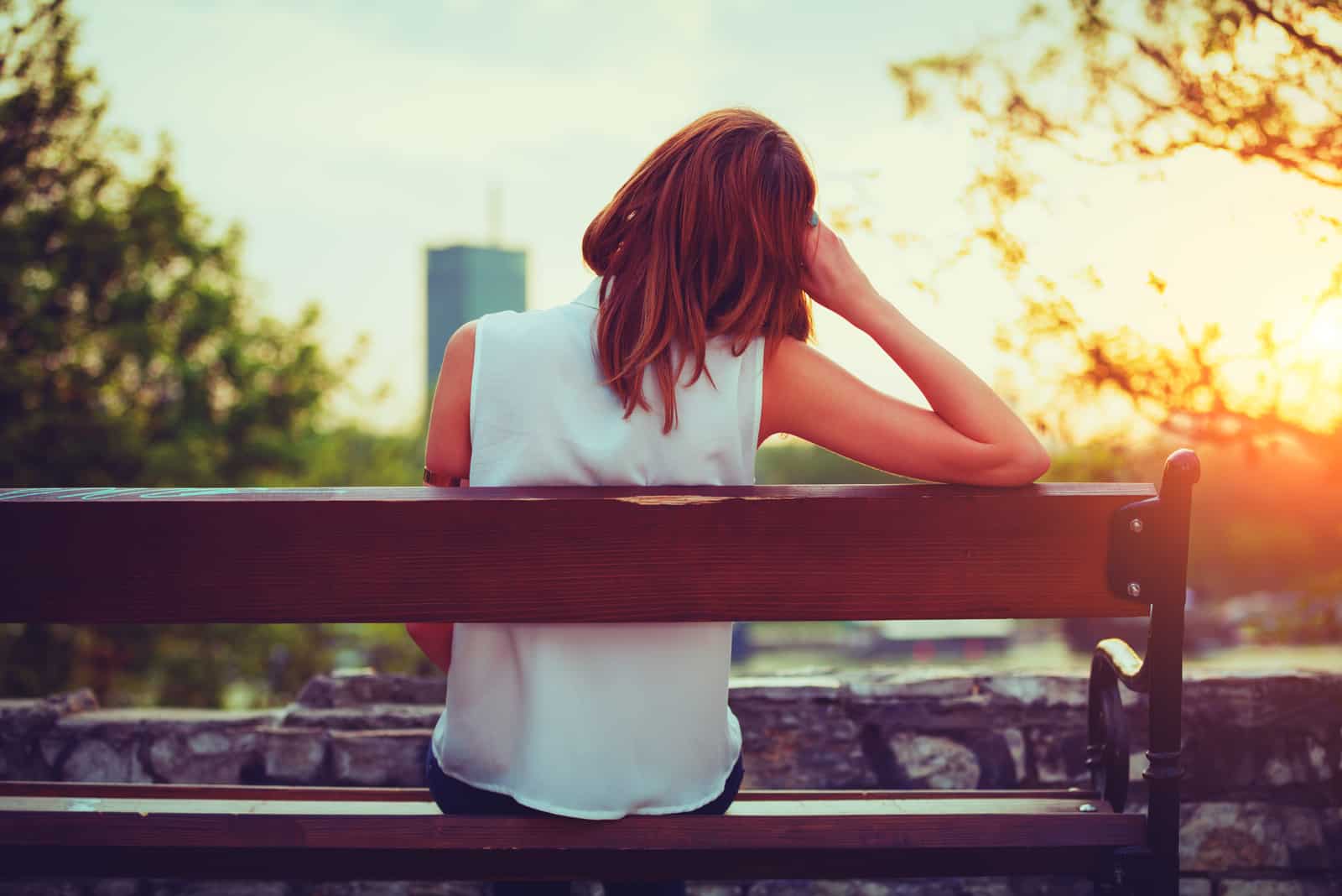 a woman with long brown hair is sitting on a bench