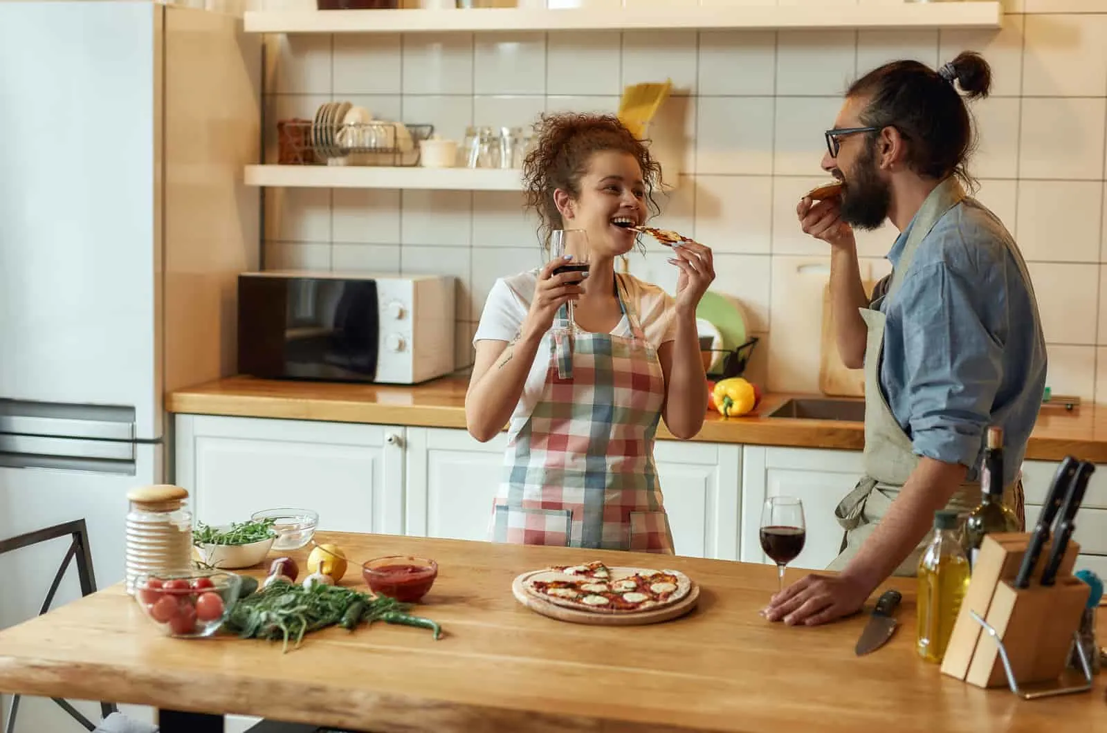 couple in kitchen eating pizza