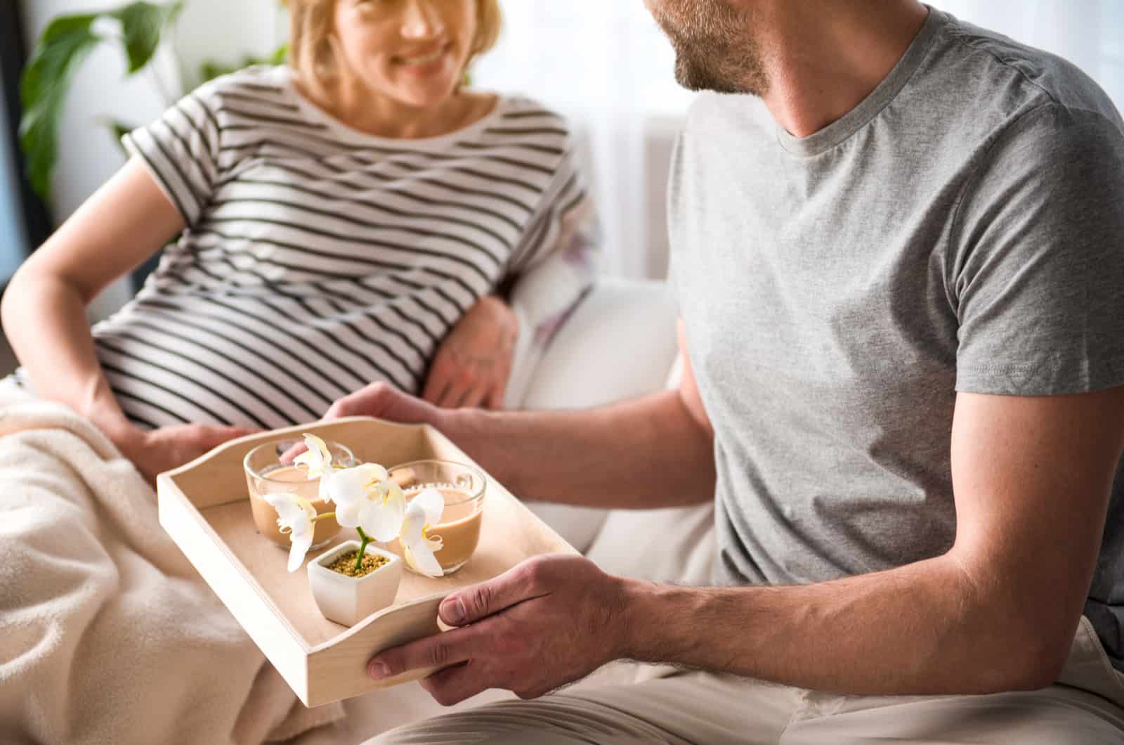 man bringing breakfast in bed to his wife
