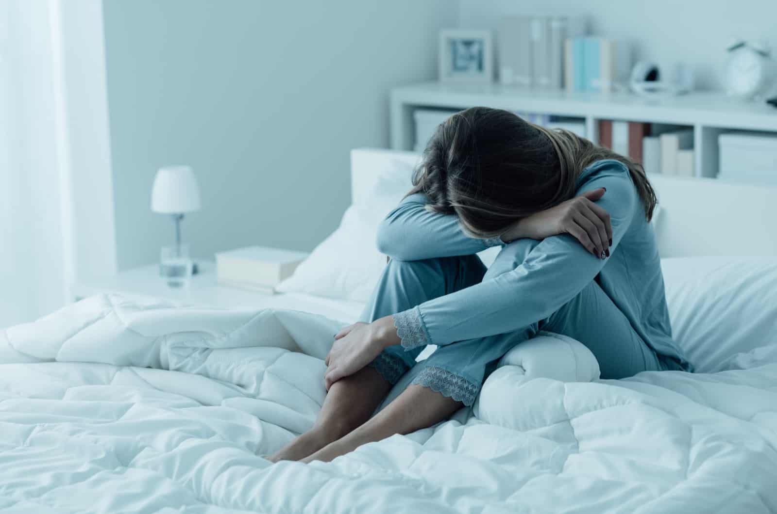 sad young woman sitting on bed