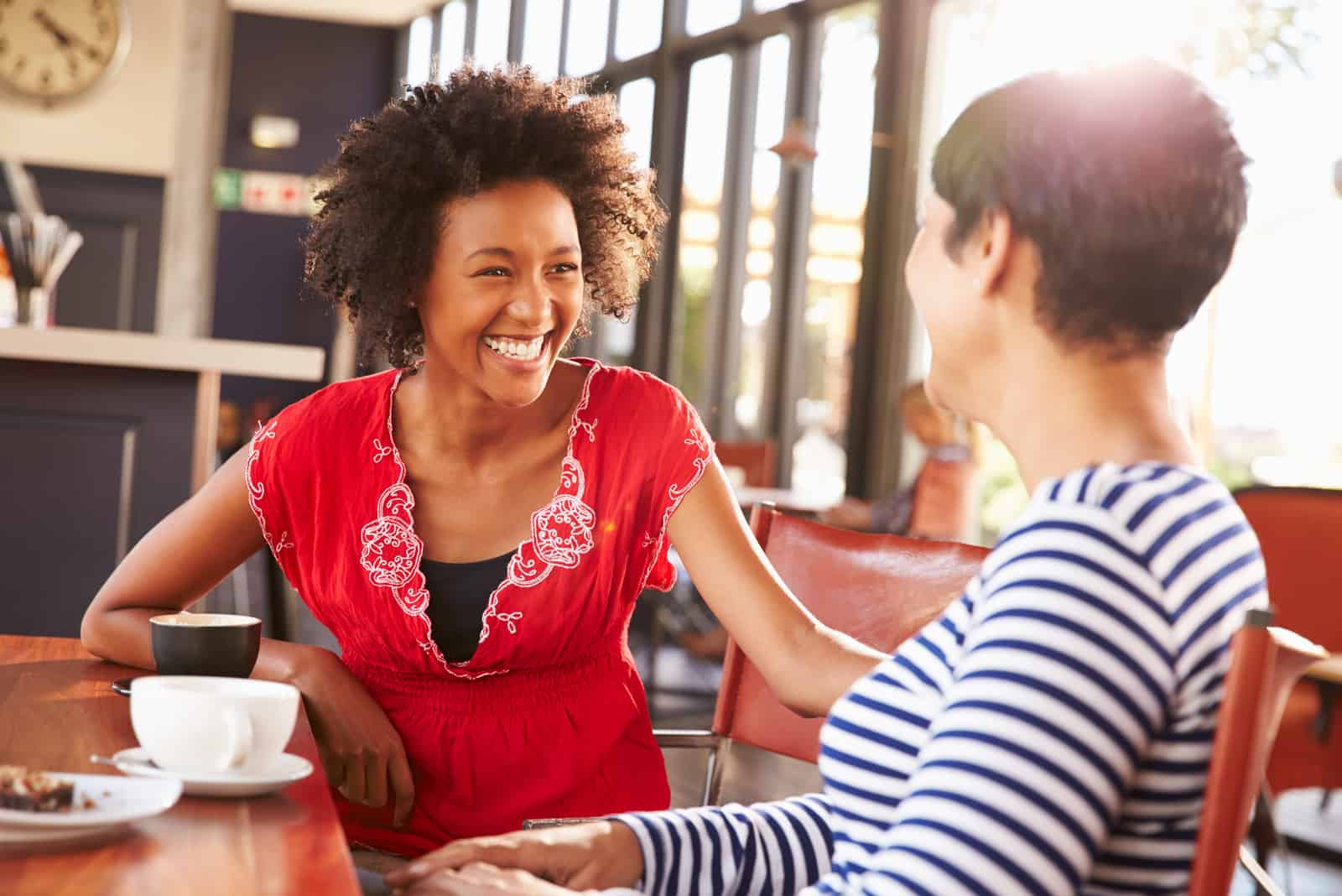 dos amigas sonrientes hablando en un café