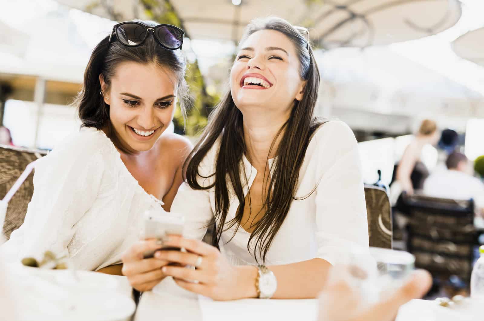 two young woman looking at phone laughing