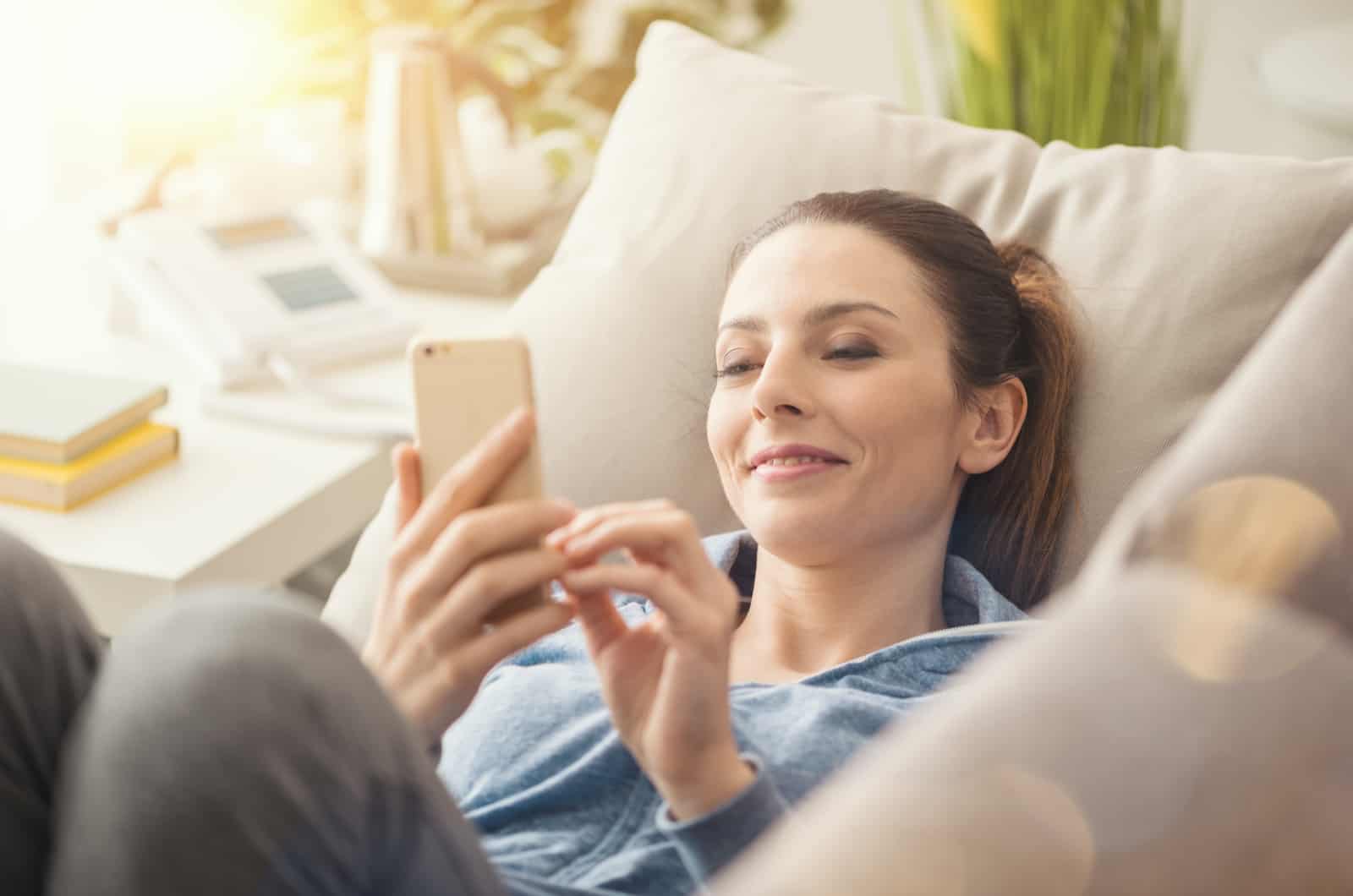 woman smiling texting on couch