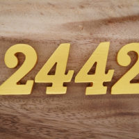 golden 2442 angel number with wooden background