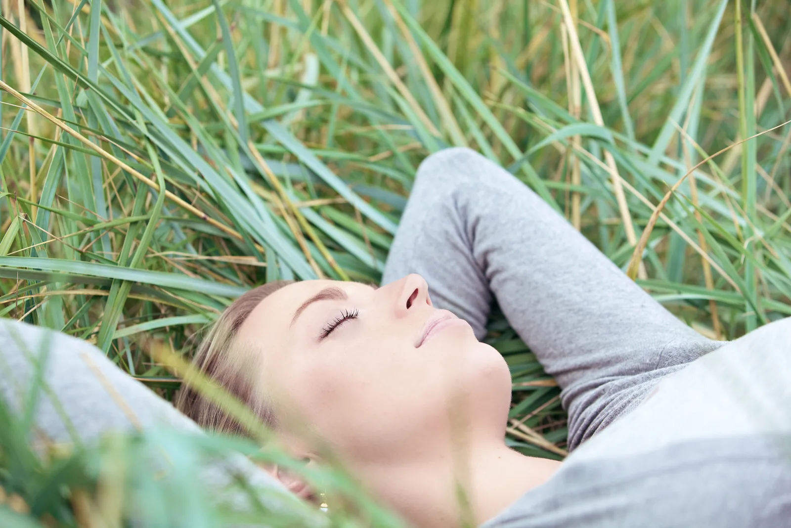 a beautiful woman lies in the grass with her eyes closed