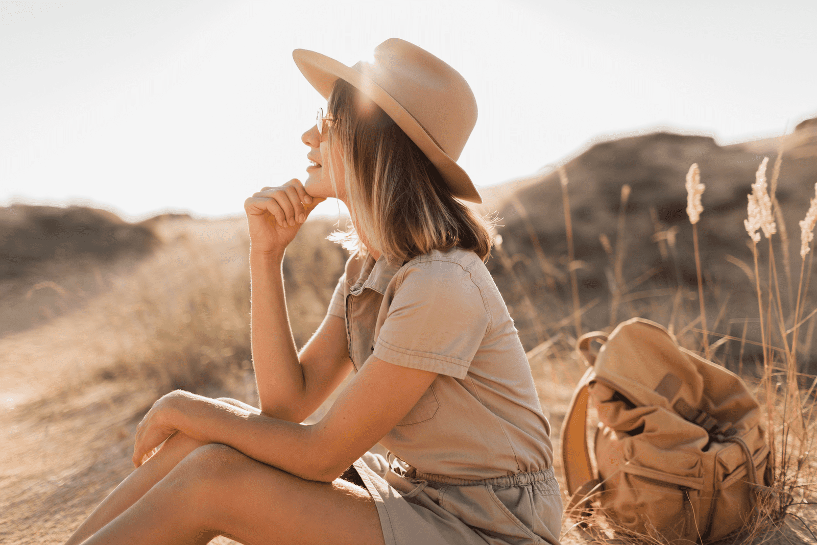 una bella donna con un cappello in testa è seduta sull'erba