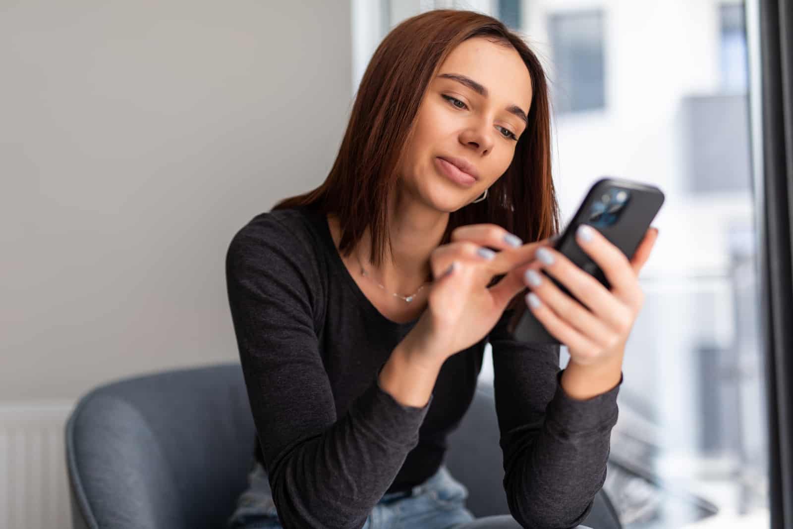 una donna con i capelli neri si siede e abbassa i tasti del telefono
