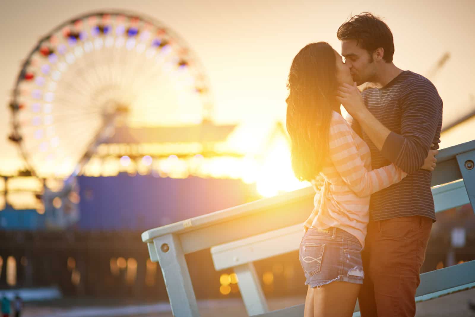 una pareja de enamorados se besa en un parque de atracciones