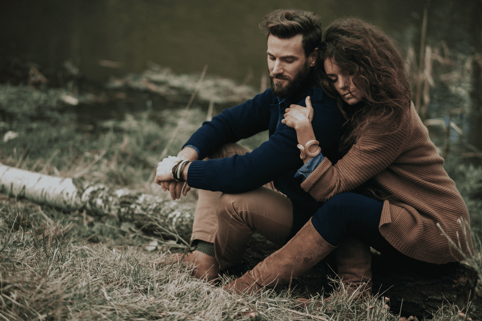 un hombre y una mujer abrazados sentados en un árbol del bosque