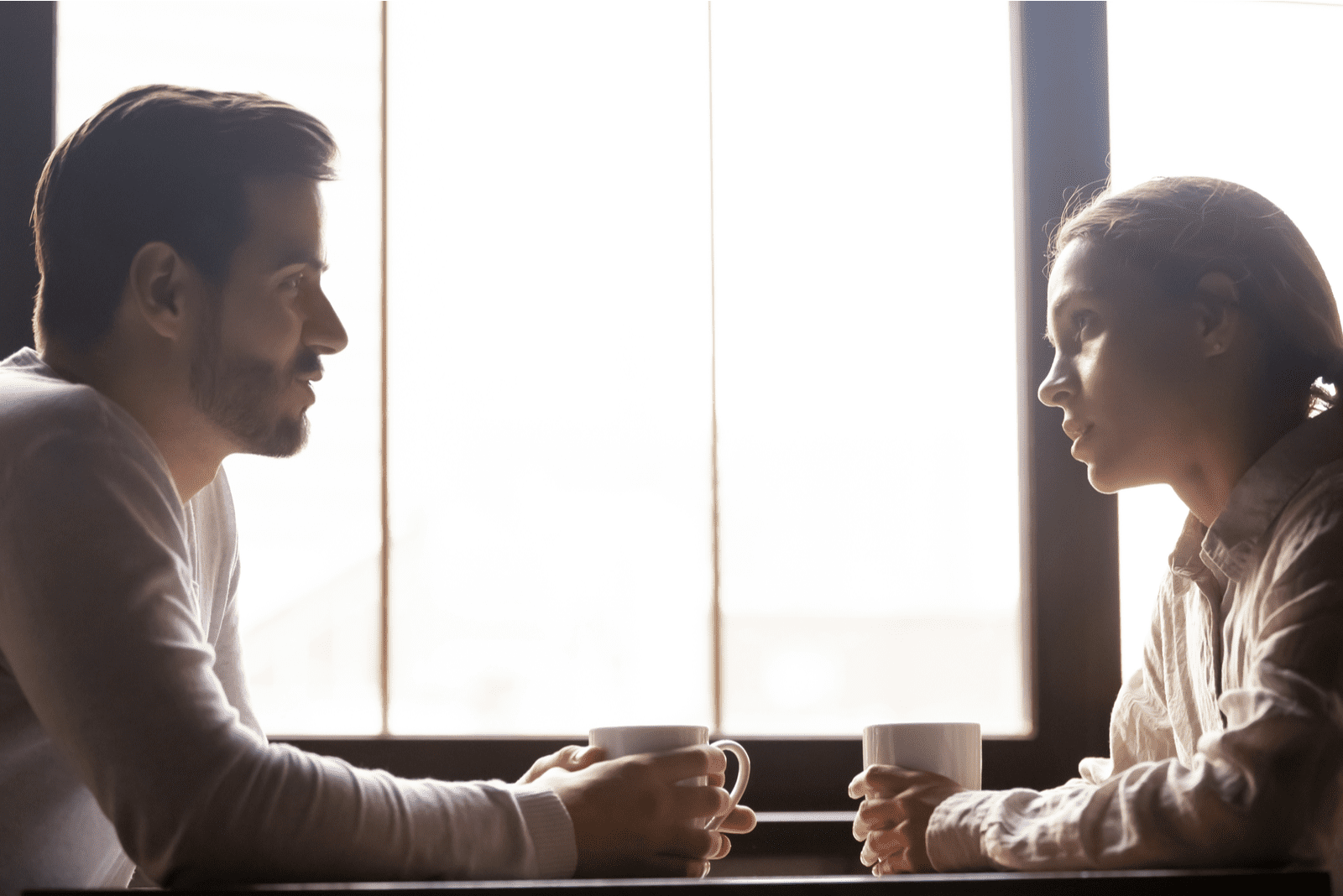 a man and a woman sit at a table and talk