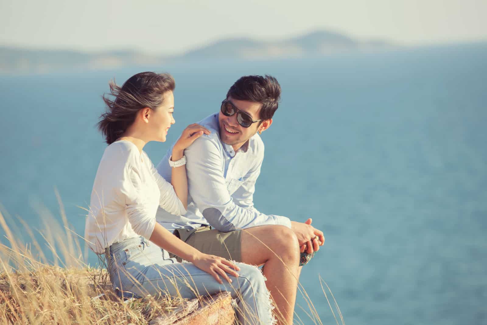 un uomo e una donna siedono su una roccia e parlano