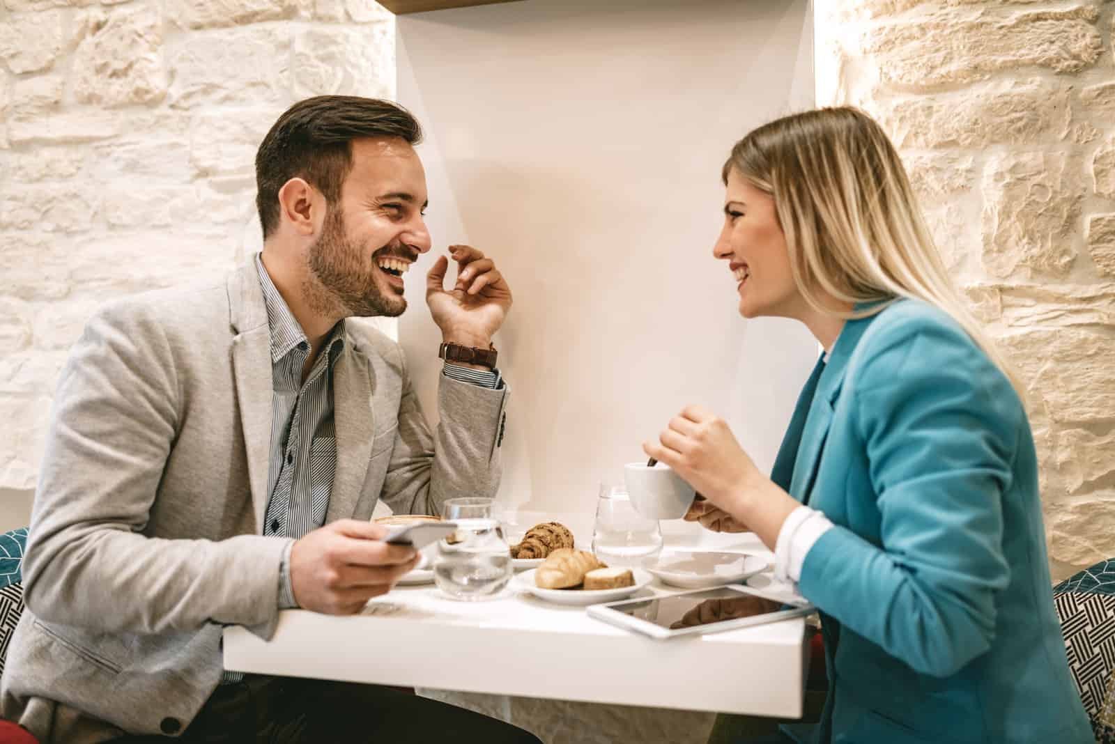 un uomo e una donna sorridenti siedono a un tavolo e parlano