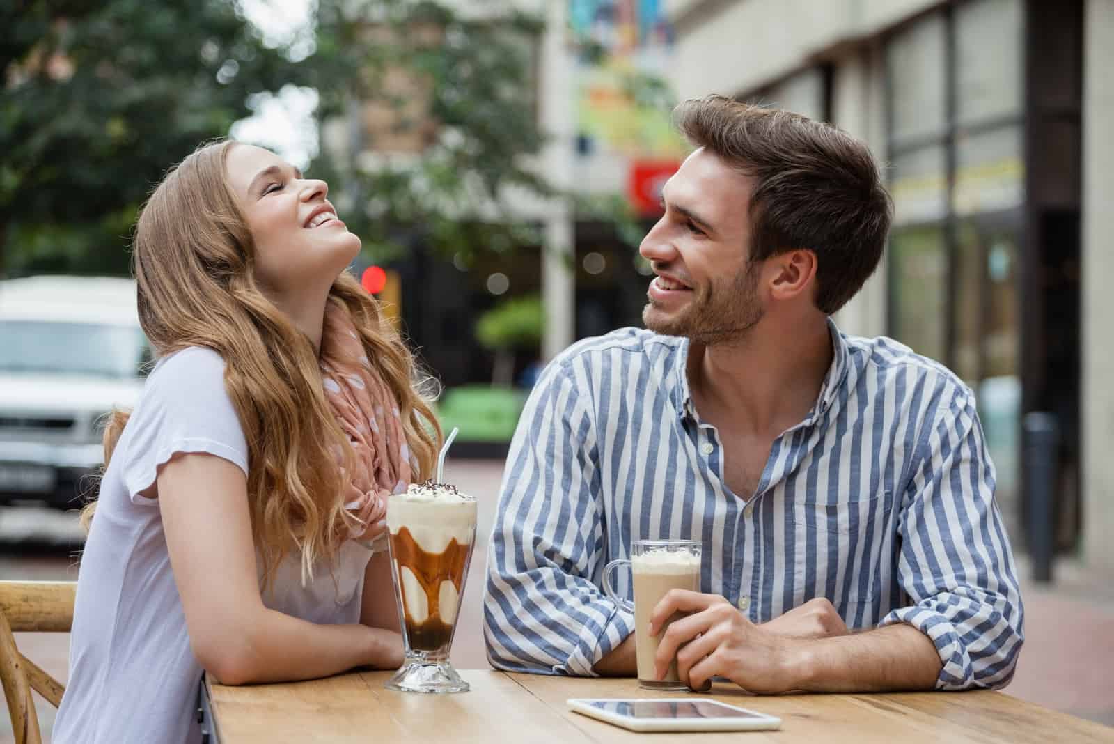 a smiling man and woman sitting outdoors talking