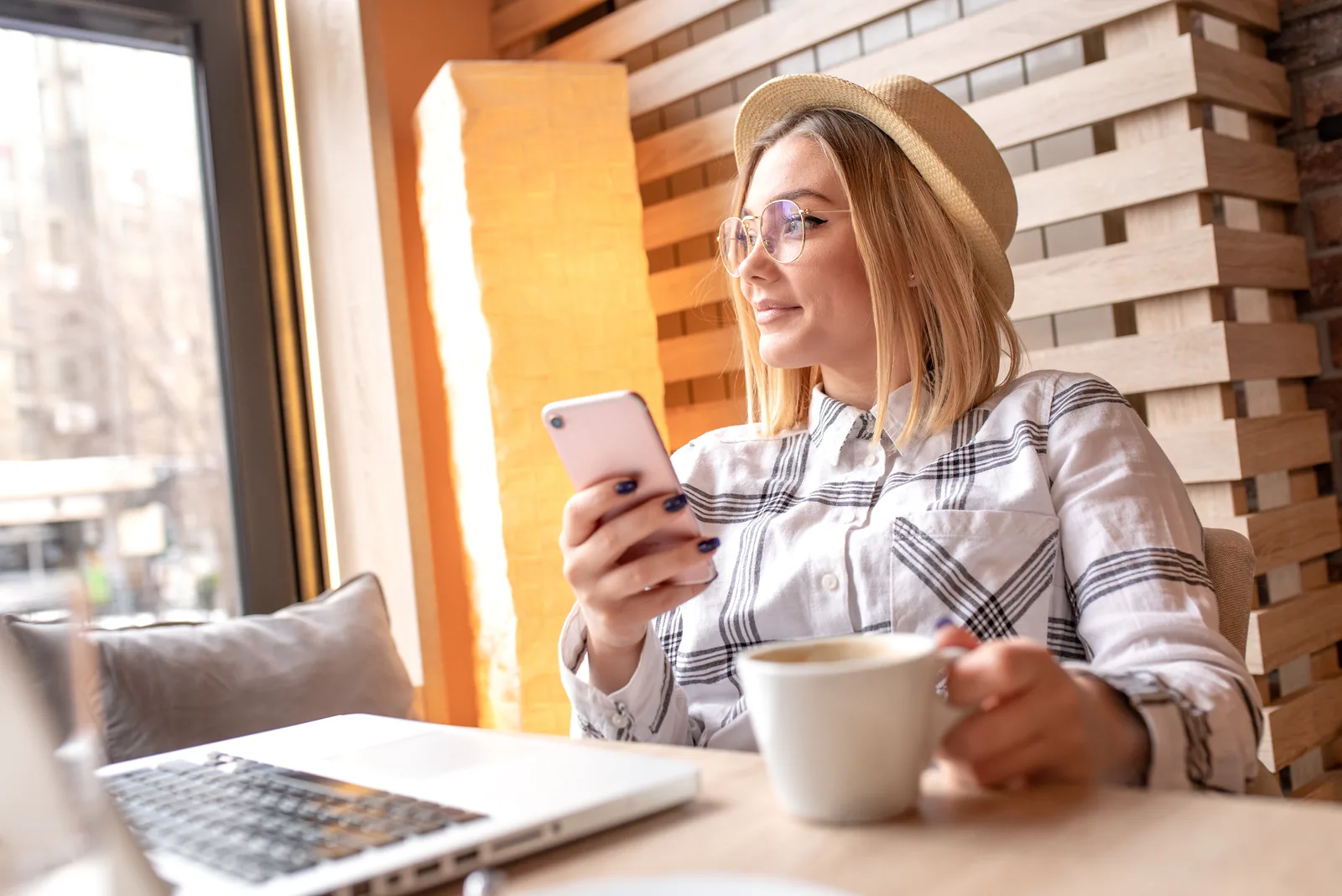 a smiling woman sitting at a table holding a phone in her hand