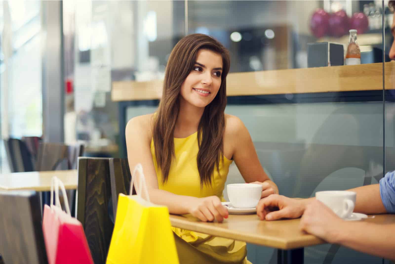 una donna sorridente seduta in un caffè con un uomo al tavolo