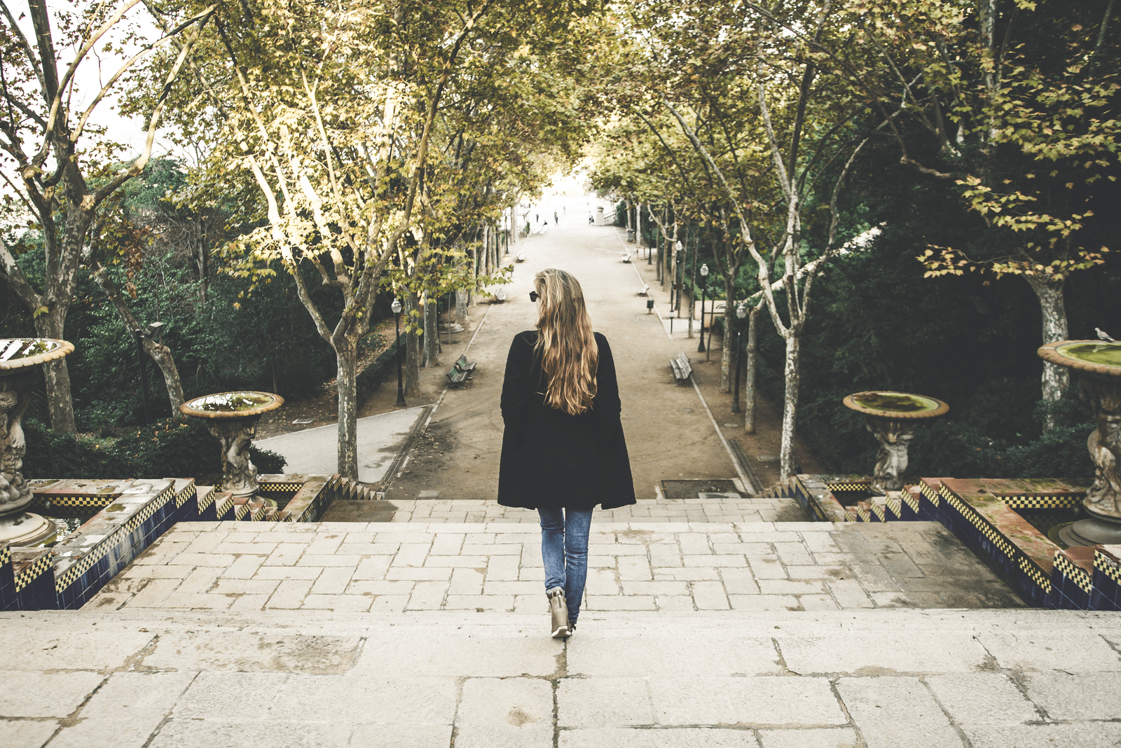 a woman in a black coat walks down the street