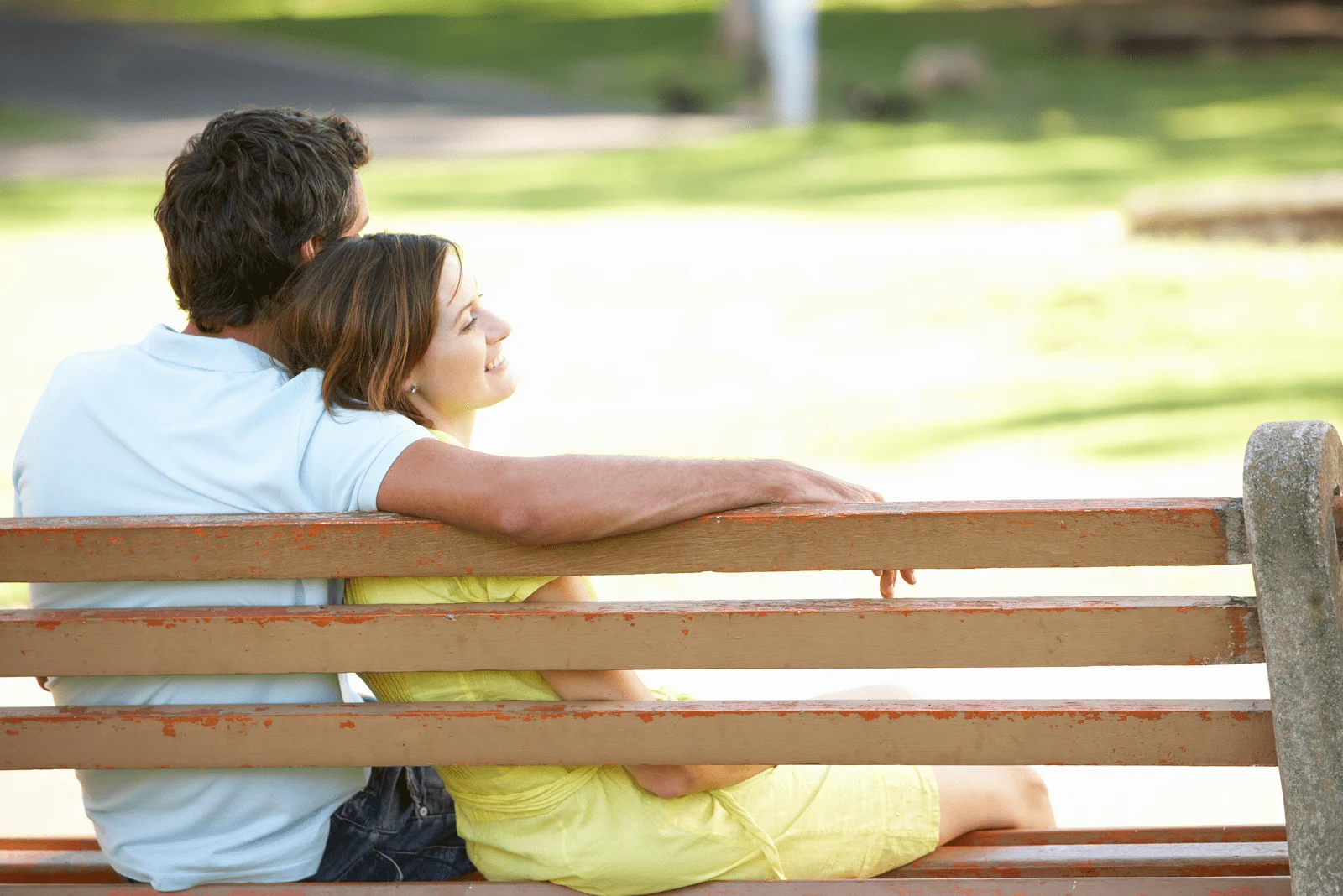 a woman sitting in the arms of a man on a park bench