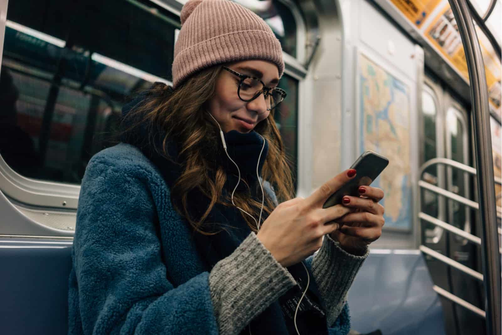 a woman with a hat on her head sits in a bus and holds a phone in her hand