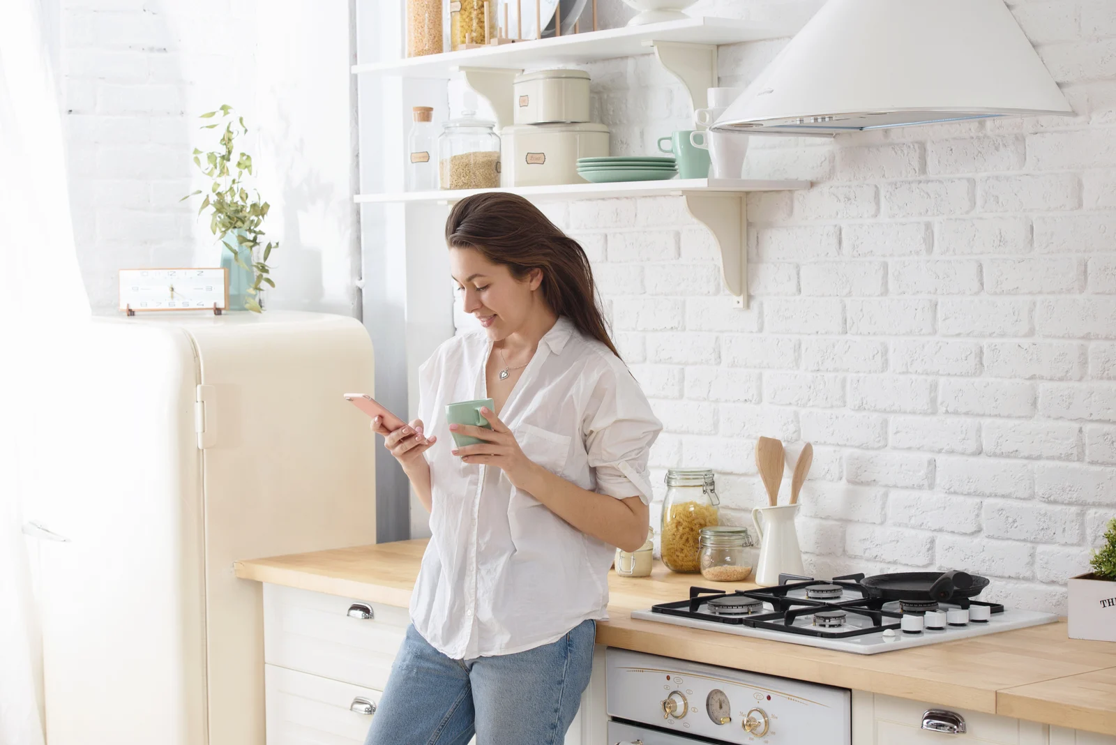 beautiful woman standing in the kitchen and button on the phone