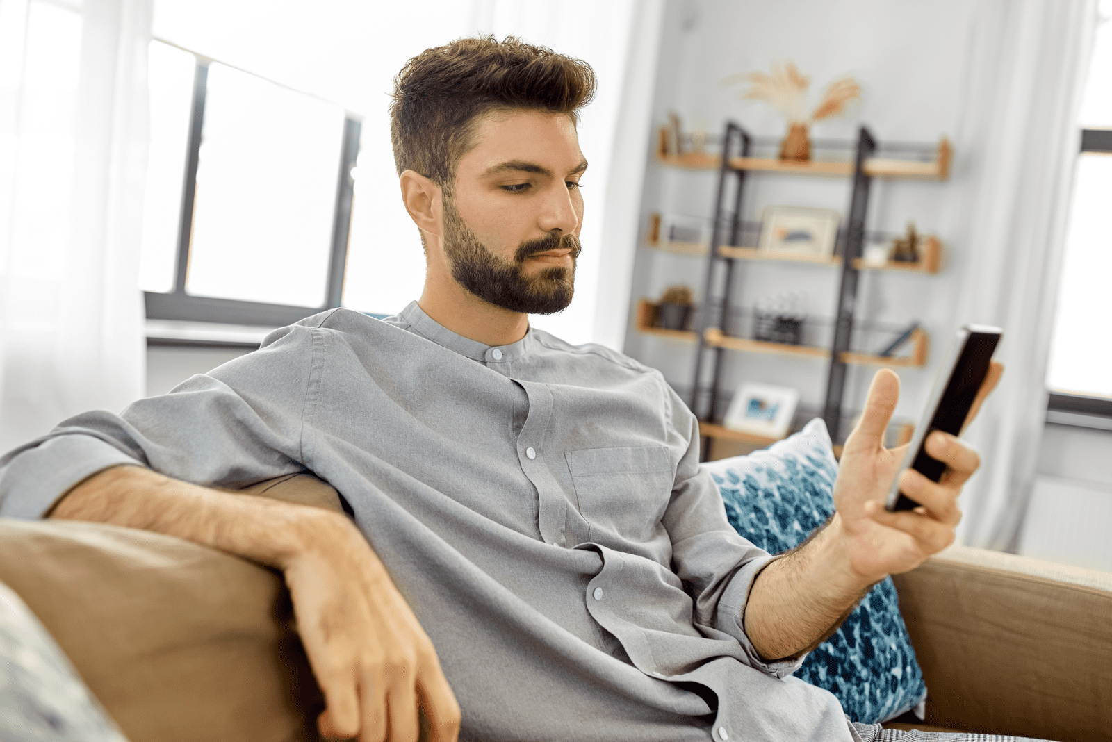 the man sits on the couch and holds the phone in his hand