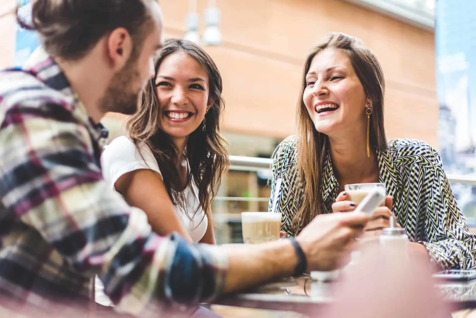two friends are sitting with a man at the table