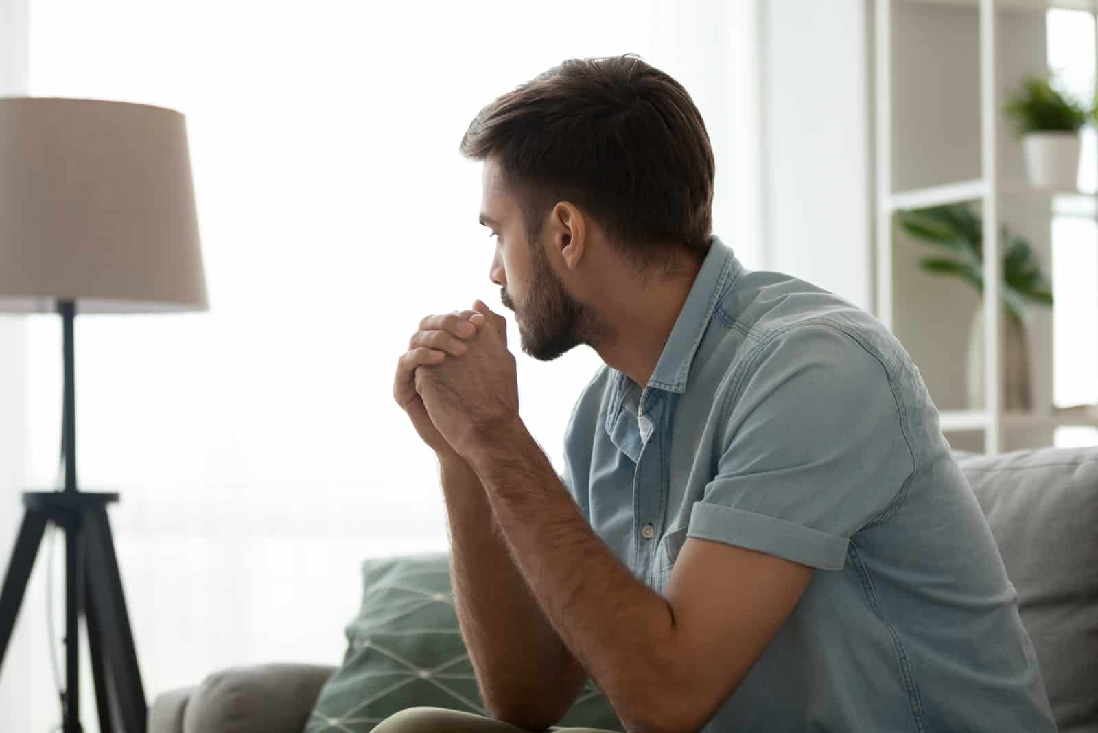 an imaginary man sits on the couch and looks away