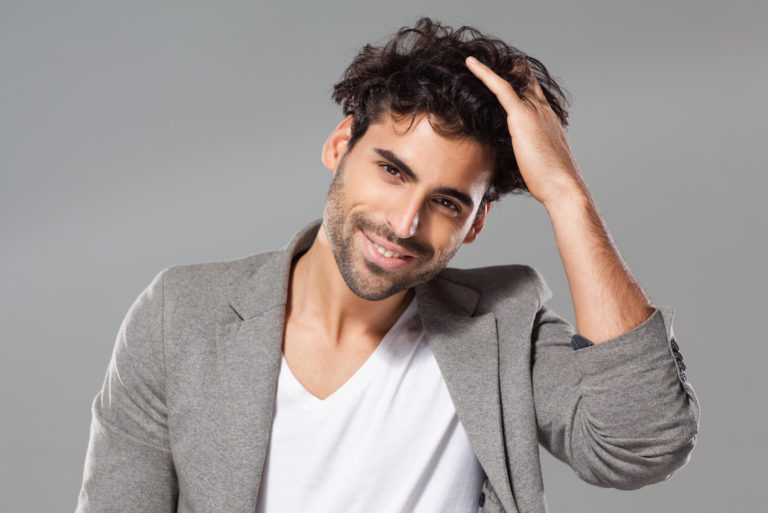 a smiling man touches his hair