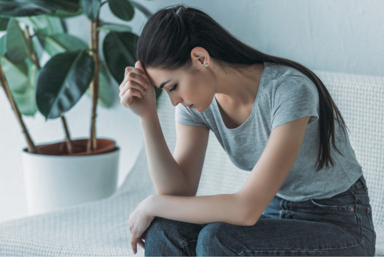 a disappointed woman with long brown hair sits on the couch