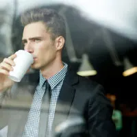 men looking through window drinking coffee