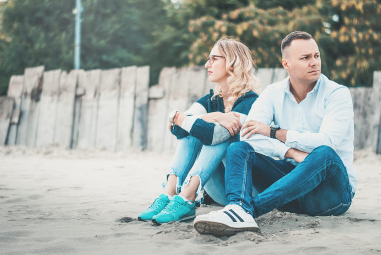 a quarreling man and woman sit on the sand