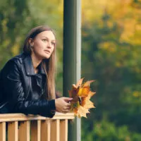 an imaginary woman leaning against a wooden fence