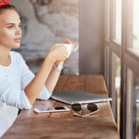uma mulher imaginária sentada numa mesa a beber café