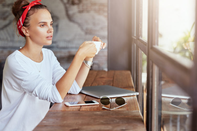 uma mulher imaginária sentada numa mesa a beber café