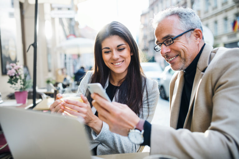 a smiling man shows a woman something on the phone