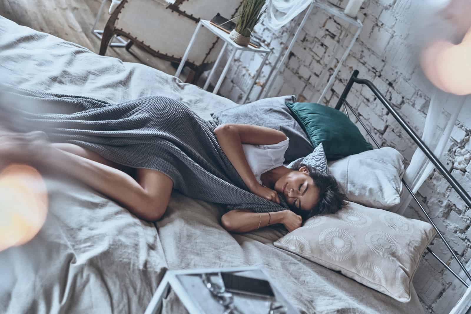 a beautiful woman covered with a blanket lies in bed