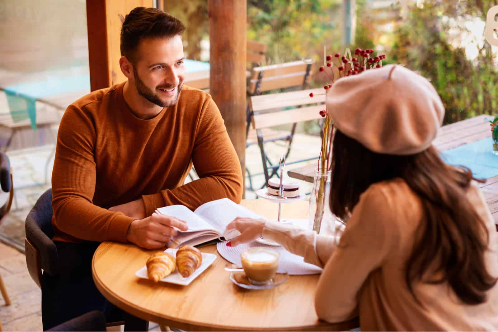 un uomo e una donna siedono all'aperto a un tavolo e parlano